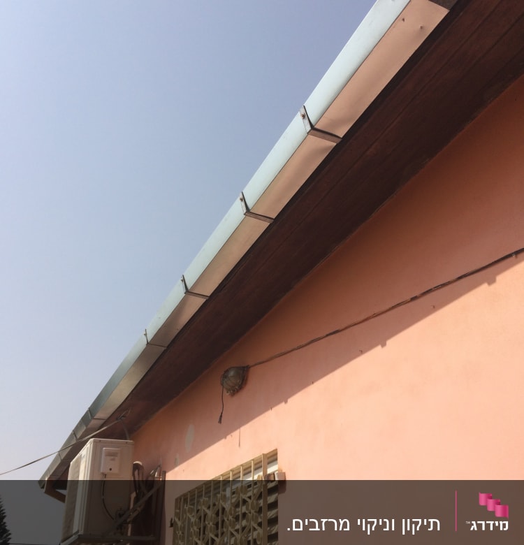 גג עם מרזב מתכת על קיר ורוד